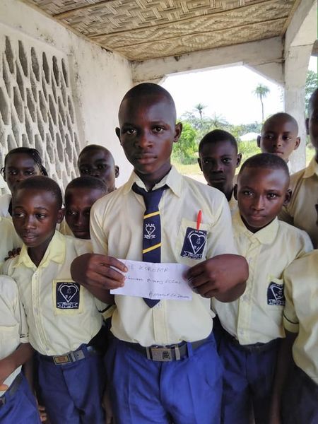 Boys in school uniform, one holding a paper, at a CARDO school programme